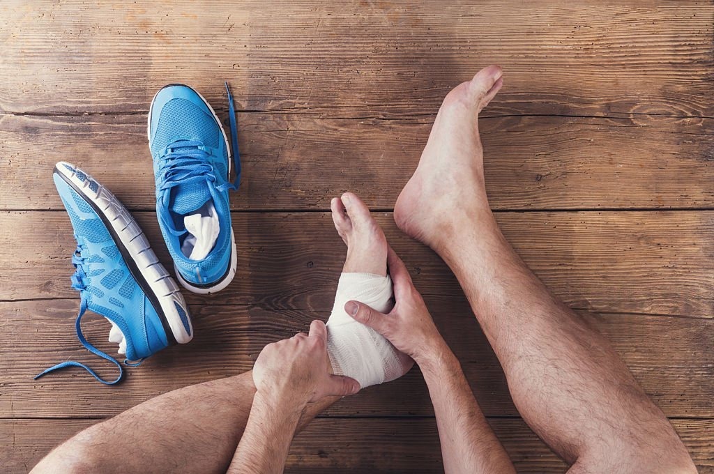 Injured runner sitting on a wooden floor